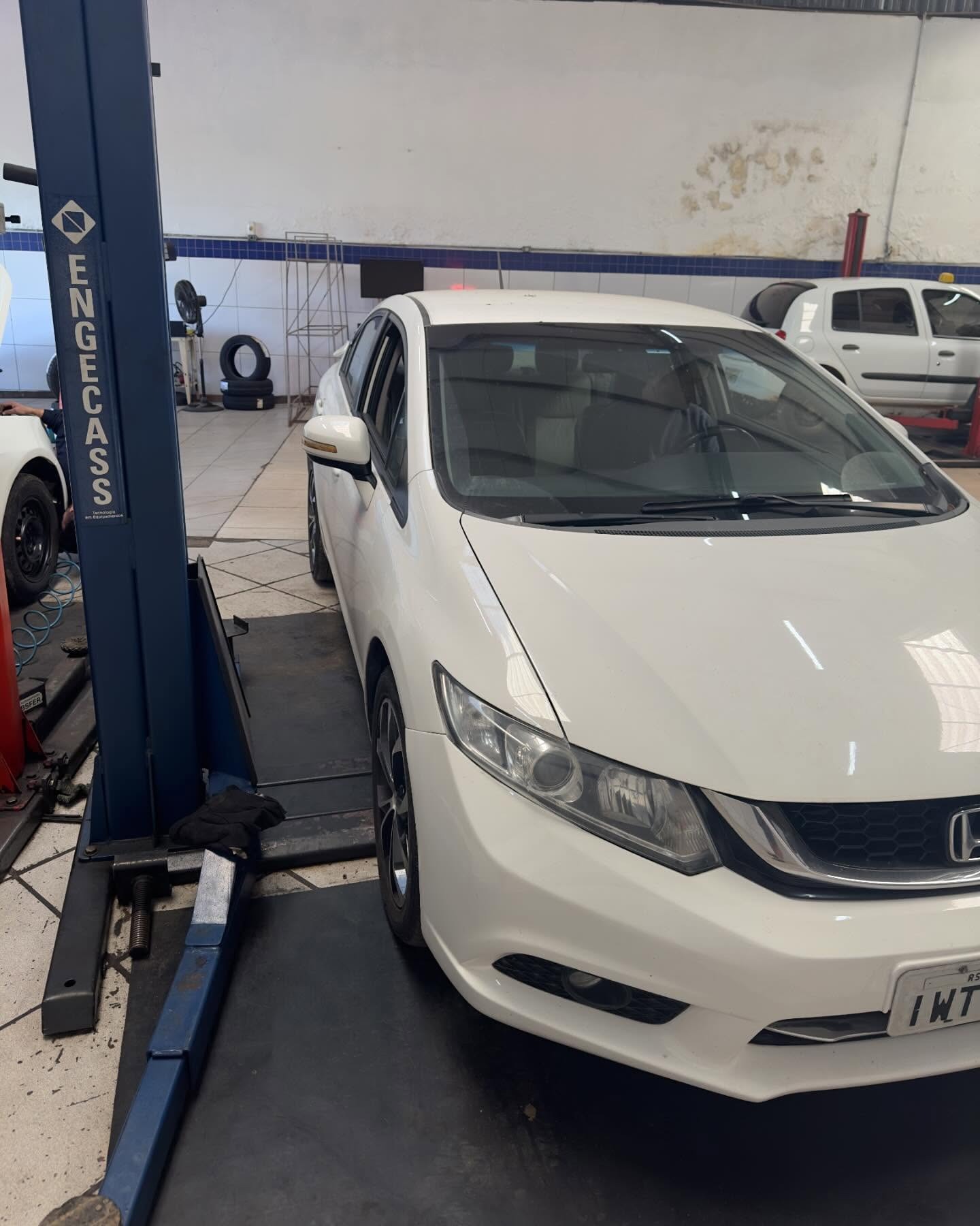 Honda Civic branco em manutenção no elevador da oficina